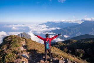 A person celebrating after climbing up a mountain.