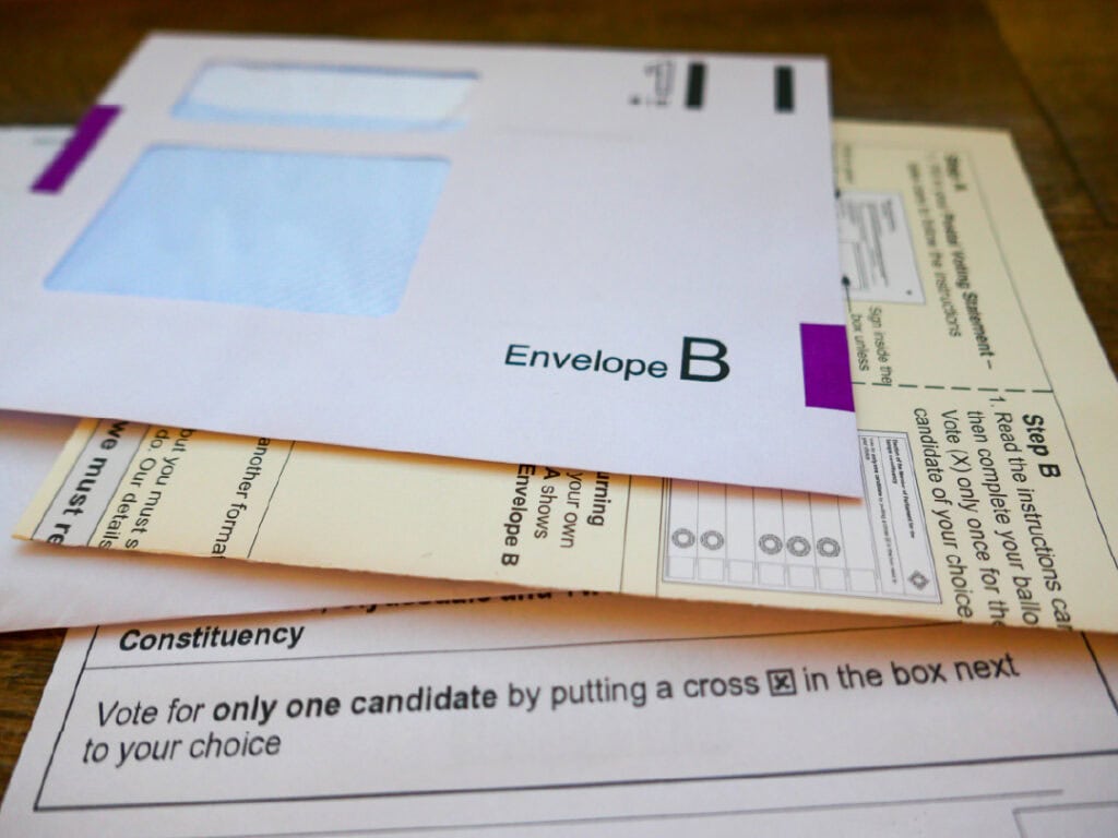 A close-up of voting materials, including an "Envelope B" and instruction sheets for casting a ballot in an election.