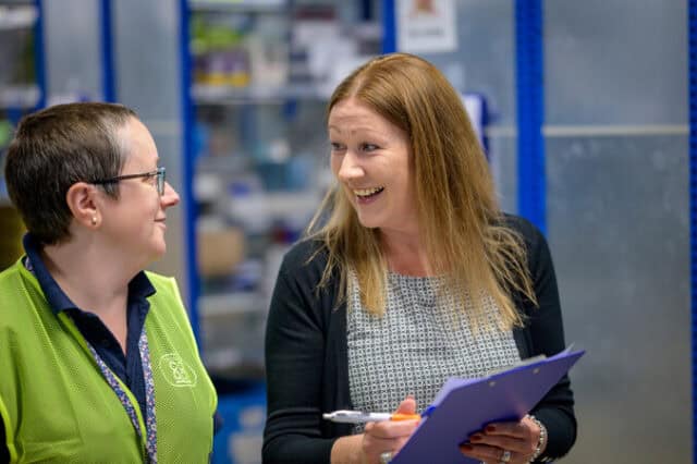 2 woman speak to each other in a warehouse