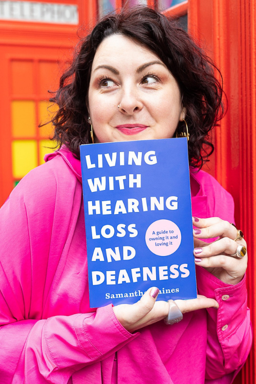 Samantha Baines, looking to the side, and holding her book: "living with hearing loss and deafness"