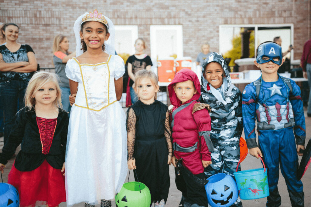 Children in fancy dress with donation buckets, and teachers and adults in the background.