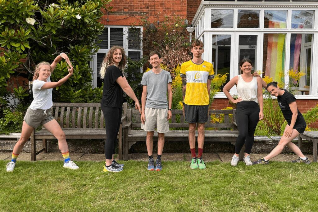 Researchers from the Cambridge Hearing Group prepare to run a half marathon. They stand in a garden and pose in the letter shapes of 'R', 'N', 'I', and 'D.'