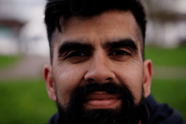 A close-up image of a man with a beard smiling