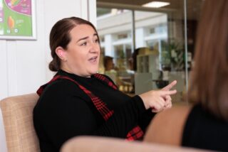 A woman using BSL sign language in discussion in a workplace.