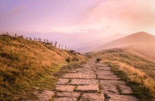 An atmospheric image of a countryside path with hills in the distance
