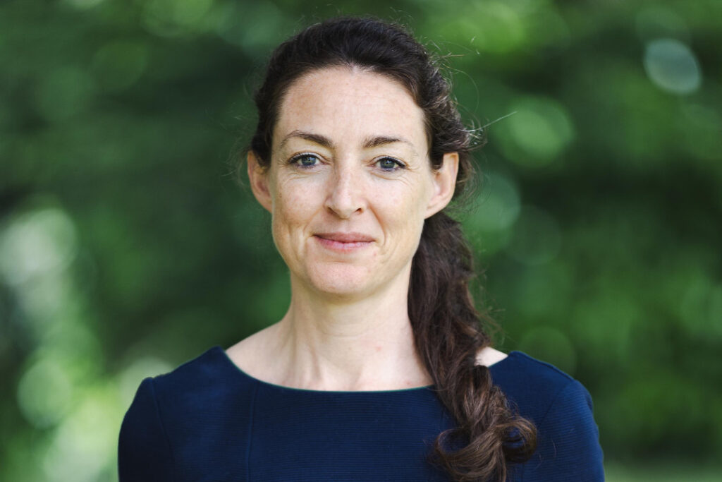 Crystal Rolfe, Director of Strategy at RNID, stands outside by greenery.
