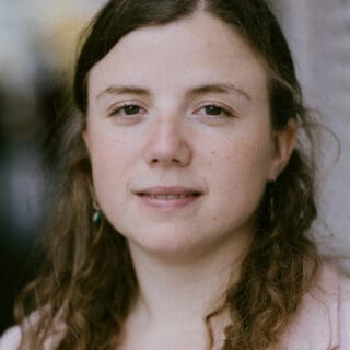 Dr Emilie Cardon. She has long brown hair and smiles.