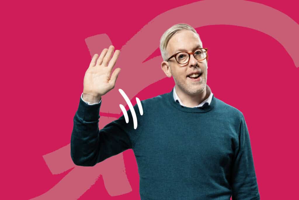 A man smiling and waving his hand