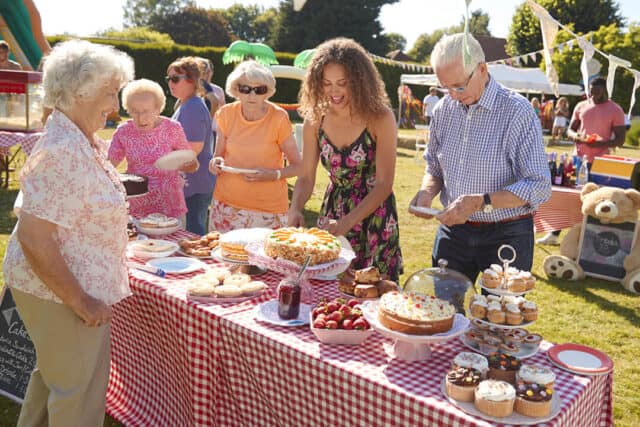 A group of people around a table of tea and cakes on a summers day