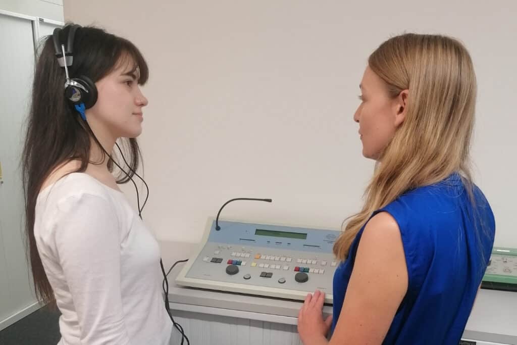 Two women stand in a laboratory facing each other.