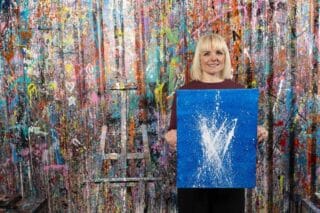 RNID storyteller, Charlotte, poses with her painting created to represent his tinnitus.
