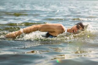 Someone swimming. They wear a swim hat and goggles.
